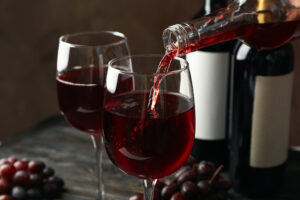 Estate Bottled Wine - Wine is poured from a bottle in glass on wooden table, close up